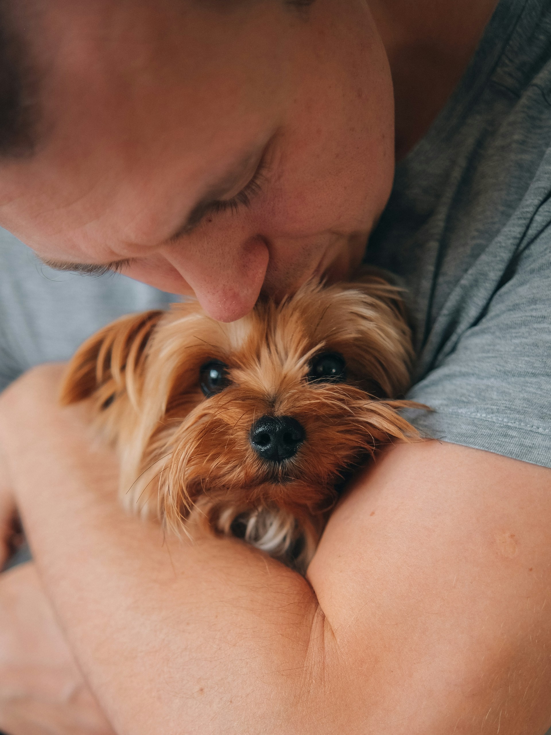 man kissing a small puppy on the forehead. seaside pups is not a broker