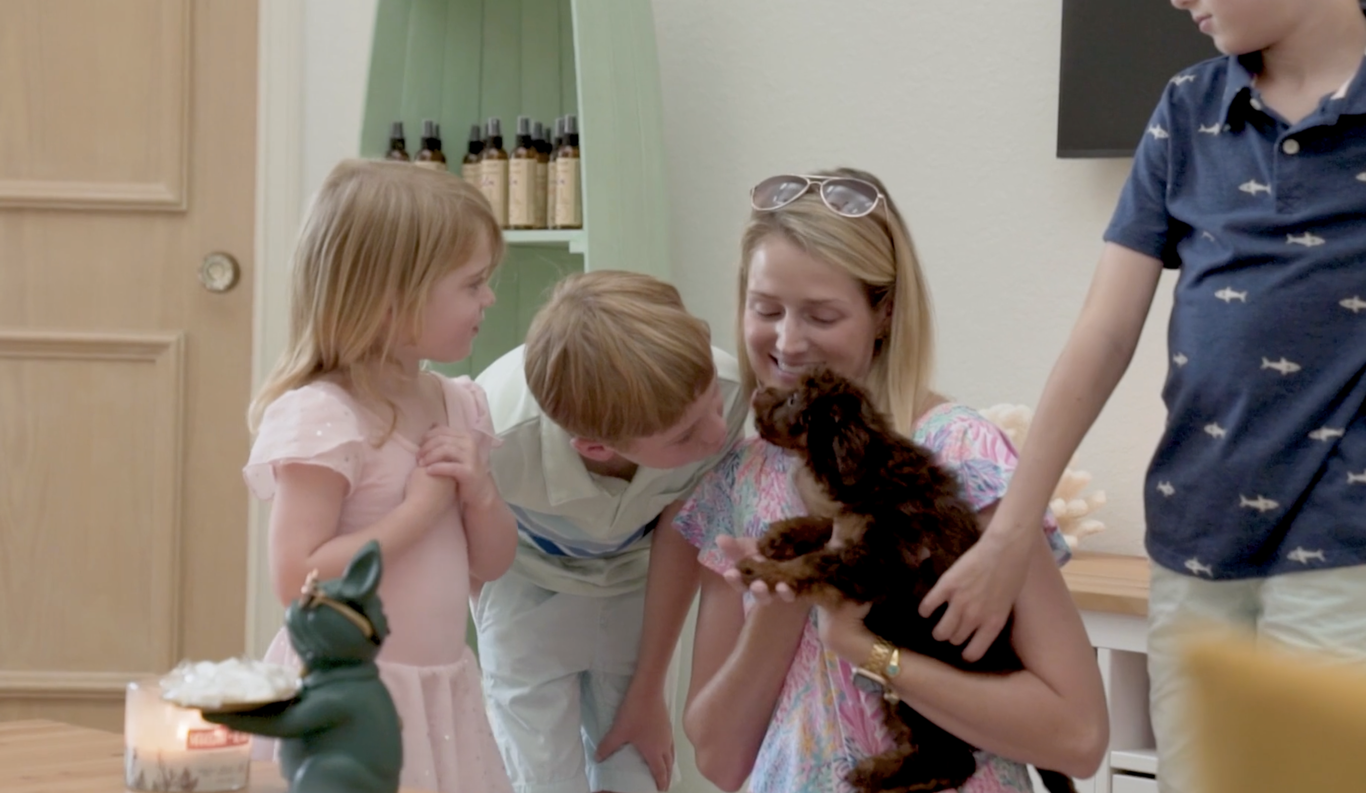 seaside pups puppy purchase - a woman and three children dotting on a small puppy